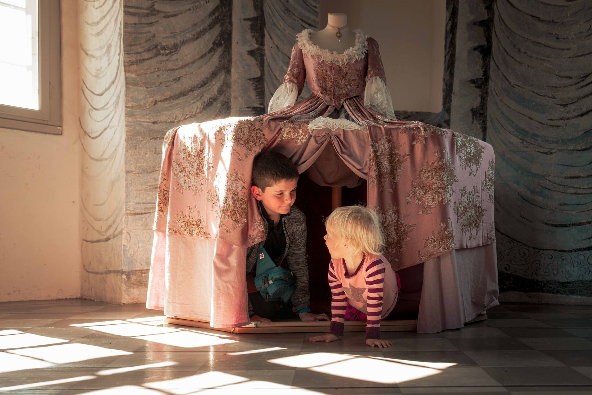 To børn leger under skørtet på en stor 1700-talskjole