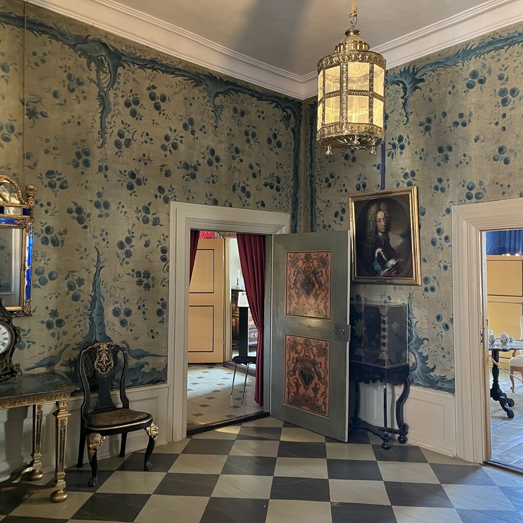 Forgemakket - entréen - på Gammel Estrup med skakternet gulv og blomstret tapet